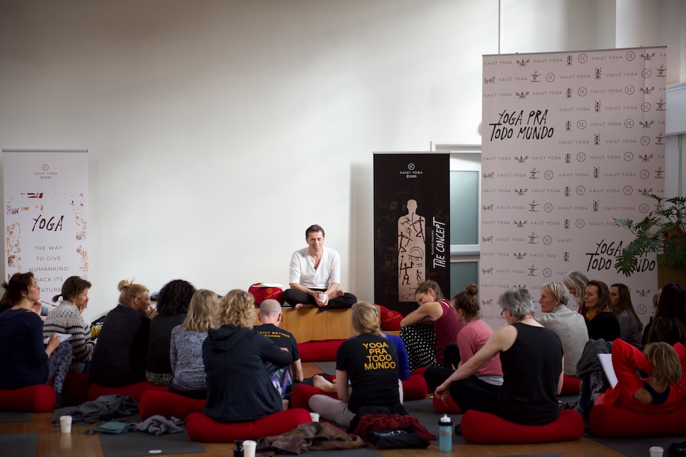 Francisco Kaiut sitting on a platform talking to a group of students seated in front of him