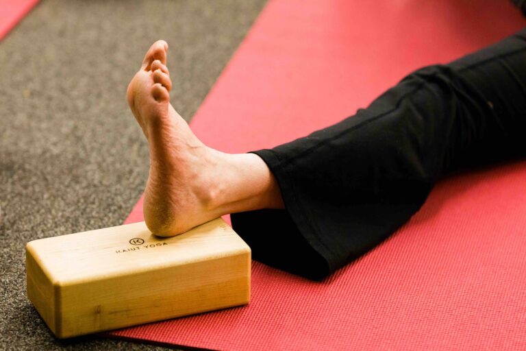 Close up of person sitting with left leg extended with heel on block